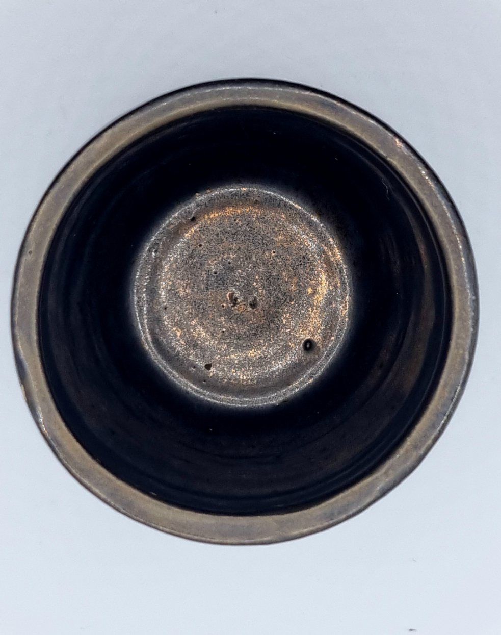 The inside of a bronze ceramic tumbler on a neutral background