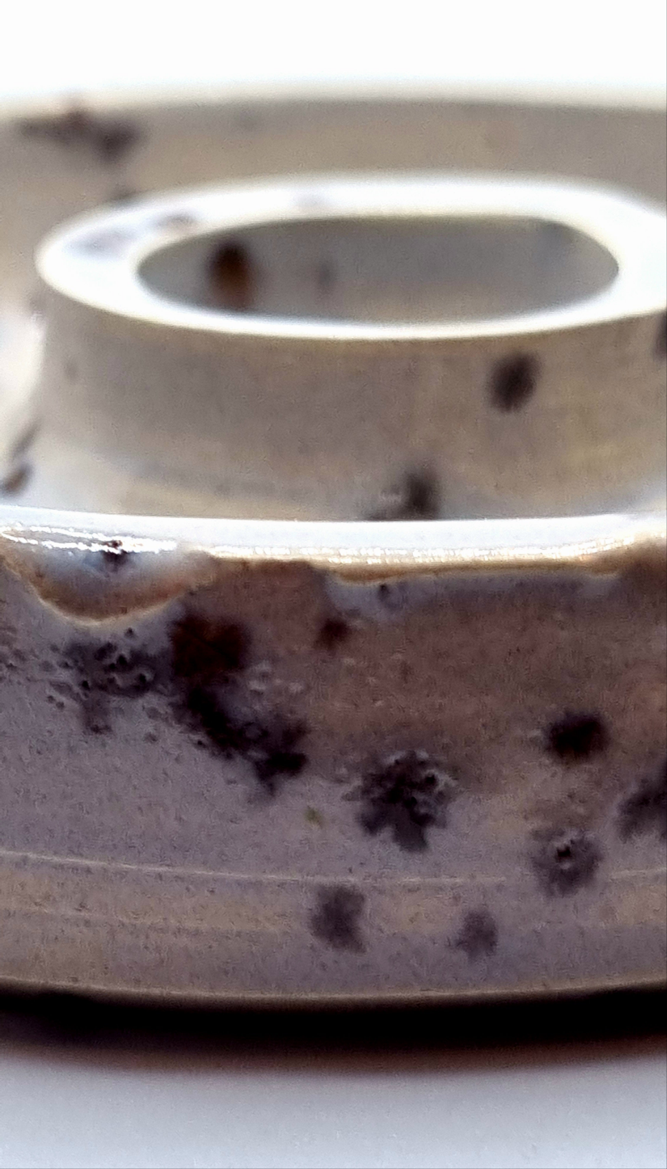 Close up of the patina on a candlestick in cream with lavender speckles on a neutral background