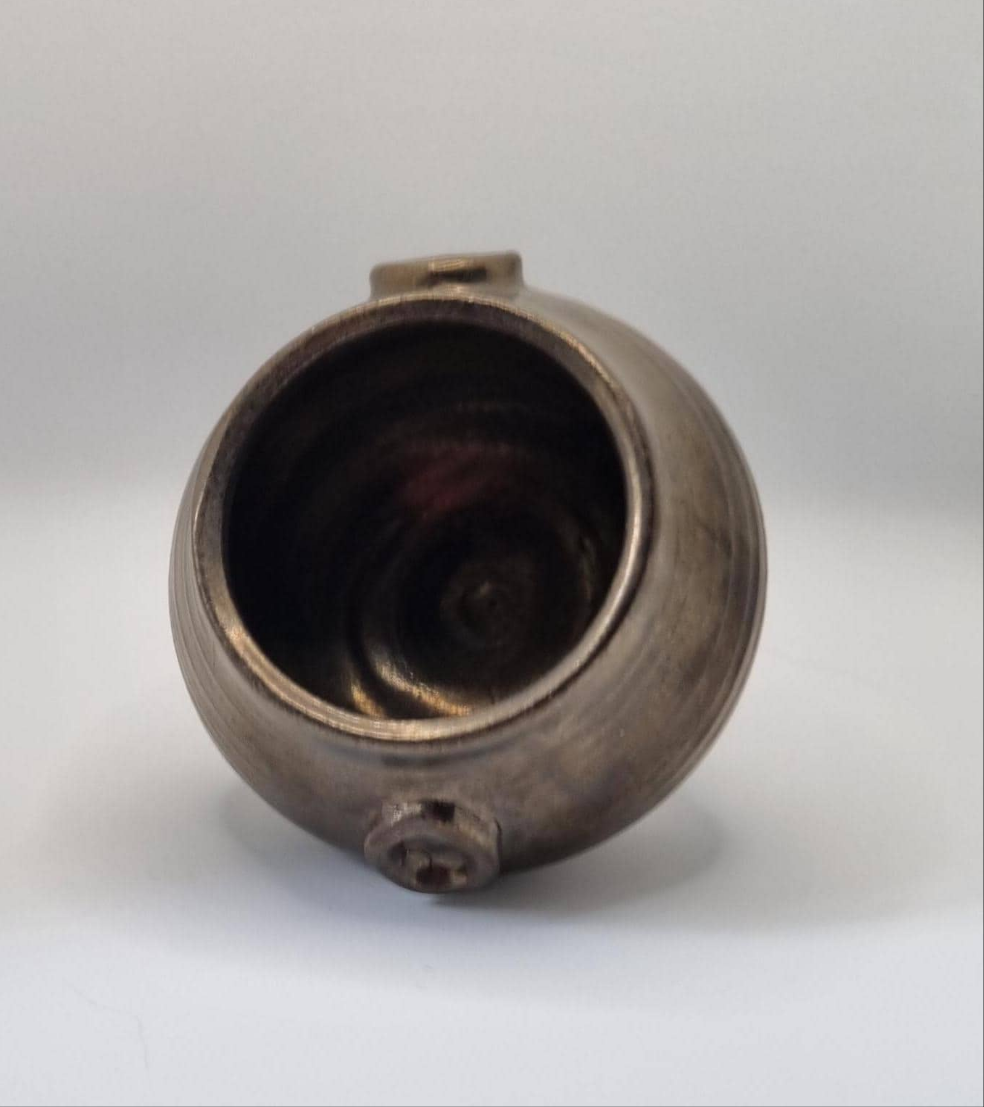 A bronze cauldron shaped tealight holder on a neutral background