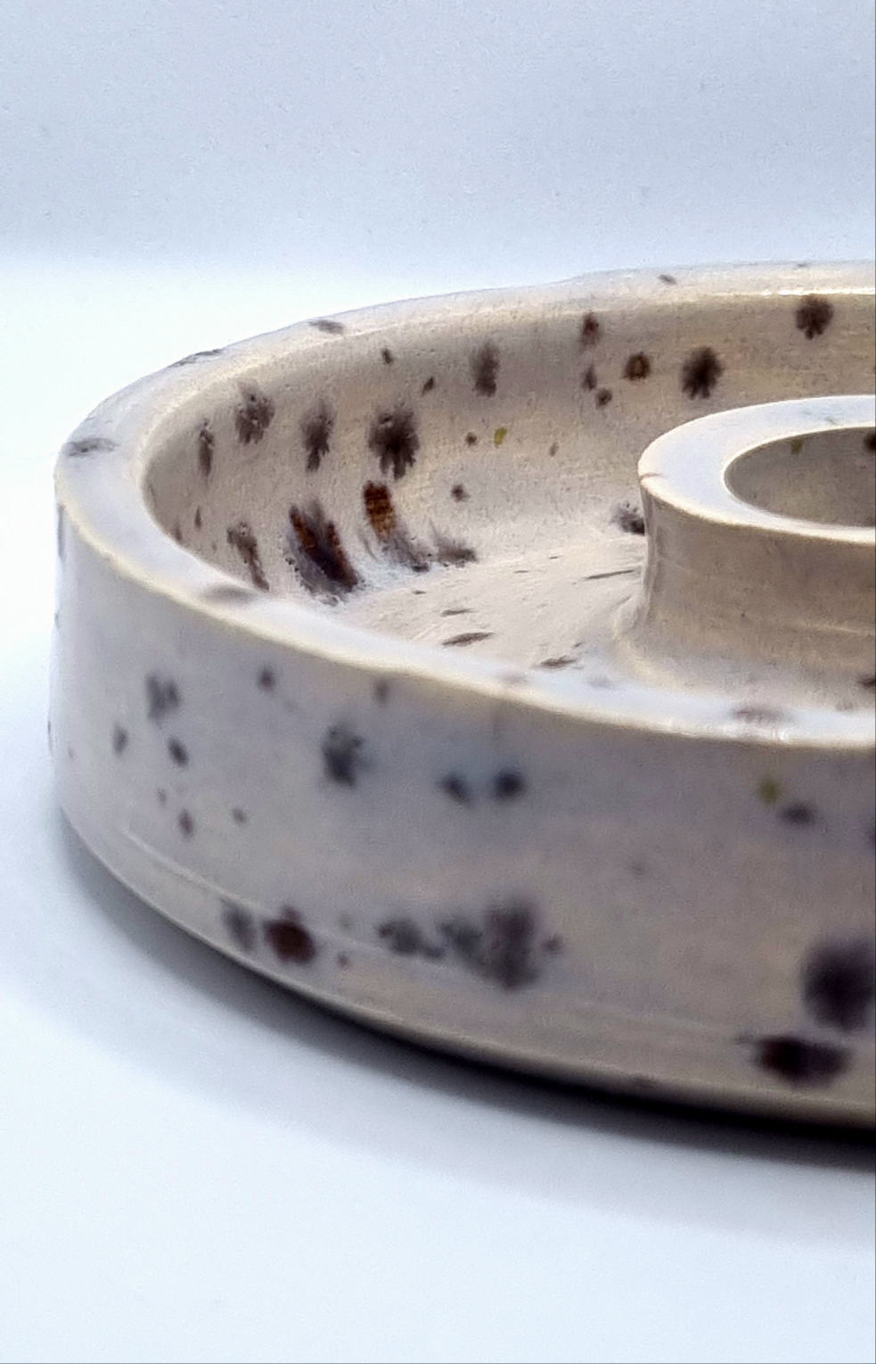 Close up of a candlestick in cream with lavender speckles on a neutral background