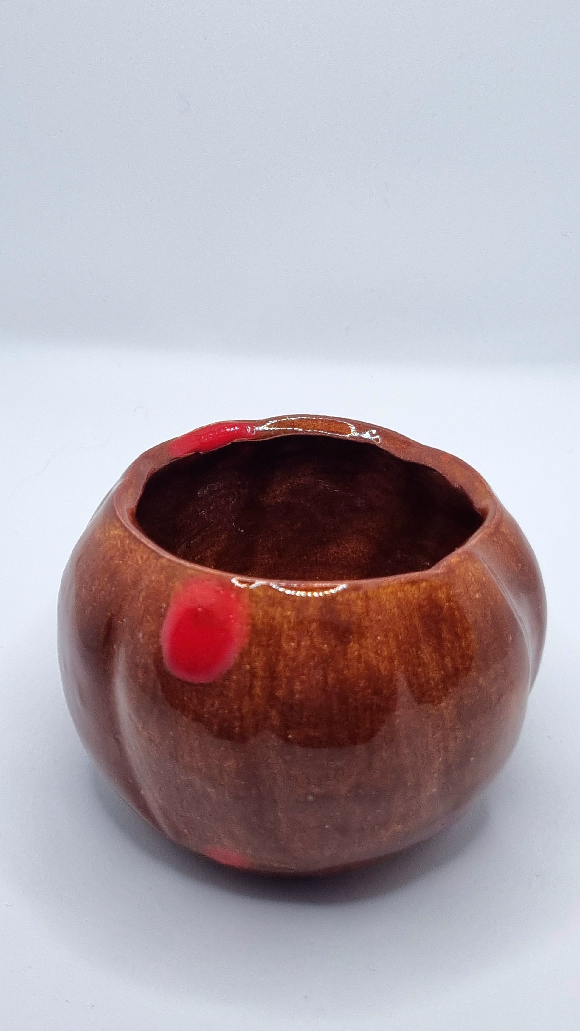 An orange pumpkin-shaped tealight holder on a neutral background