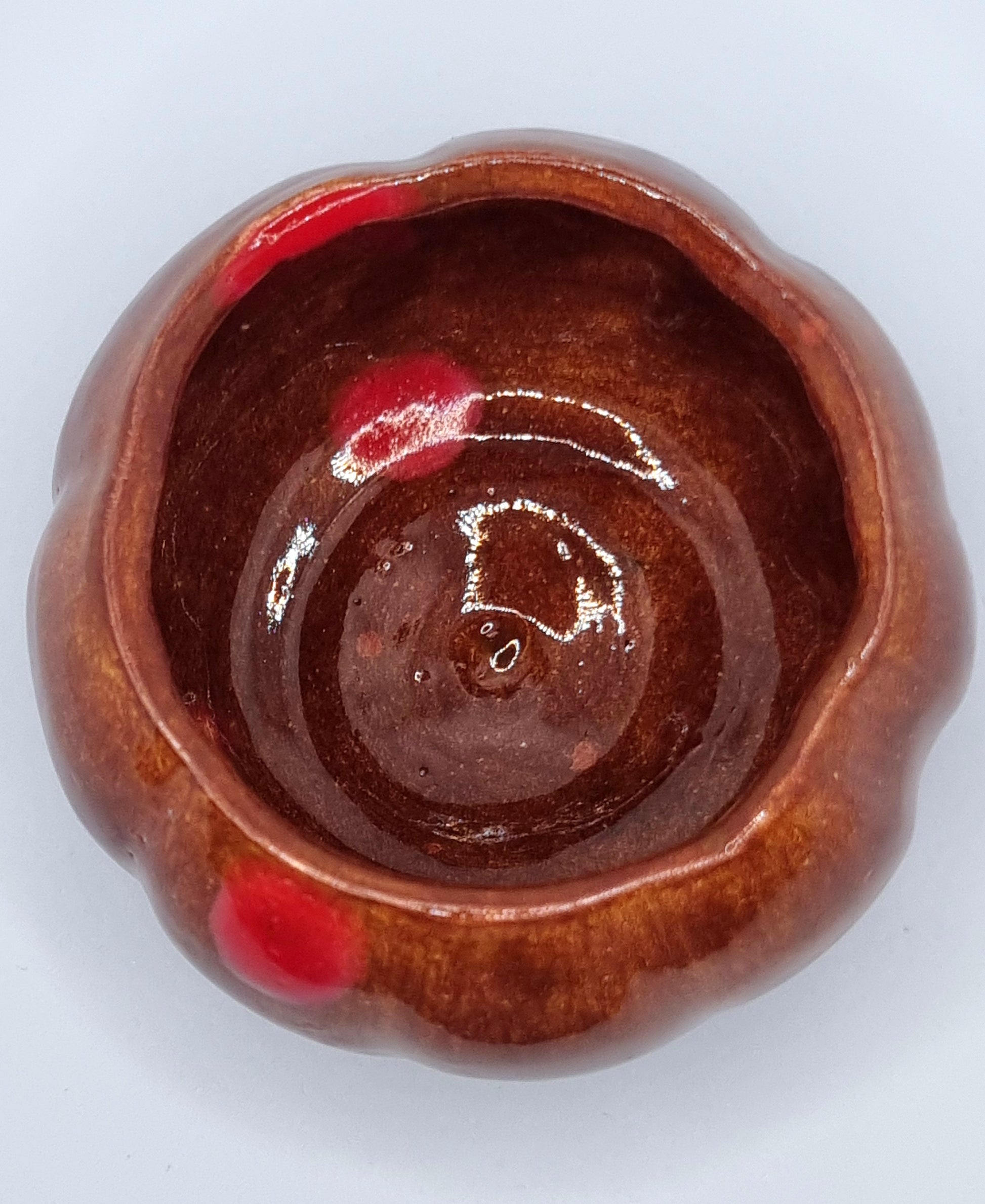 An orange pumpkin-shaped tealight holder on a neutral background