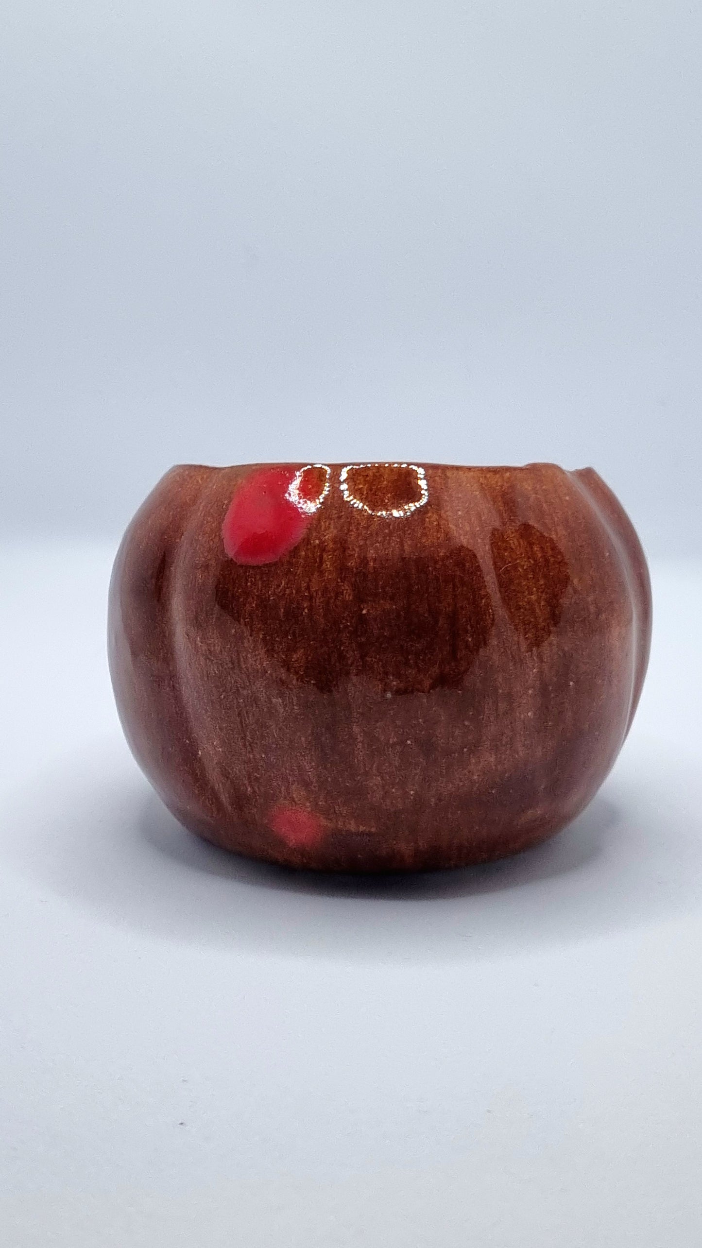 An orange pumpkin-shaped tealight holder on a neutral background