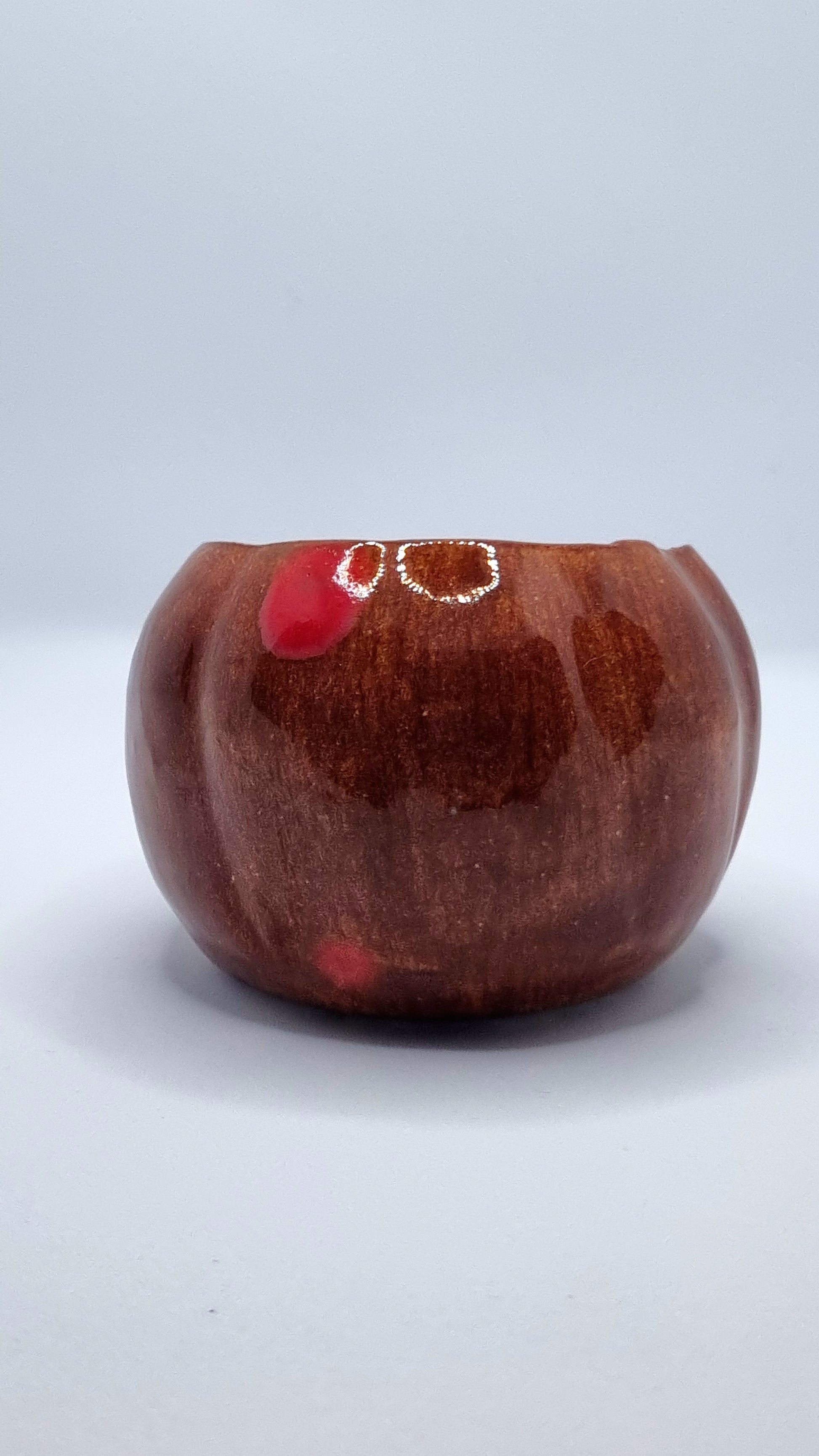 An orange pumpkin-shaped tealight holder on a neutral background