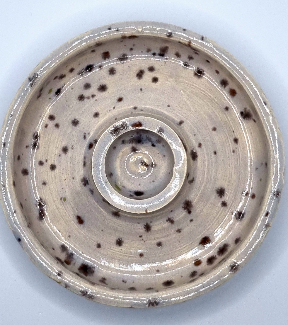 Candlestick from above in cream with lavender speckles on a neutral background