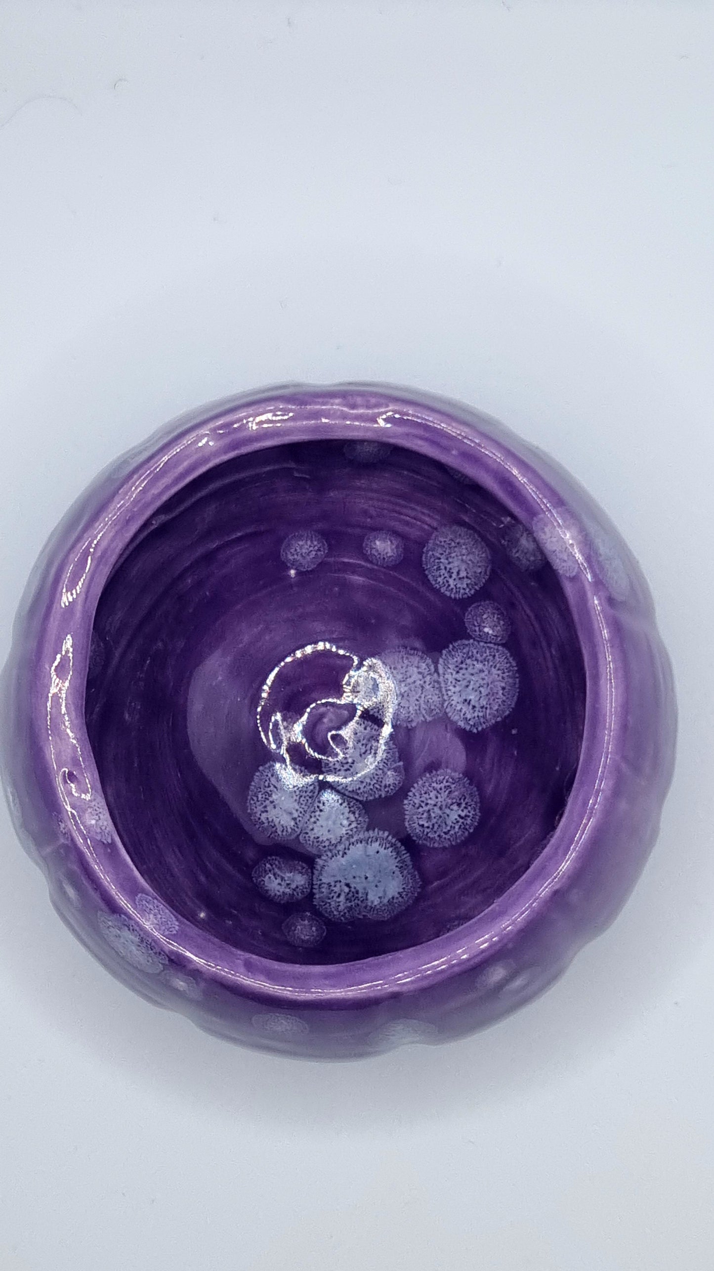 A purple, pumpkin-shaped tealight holder from above on a neutral background